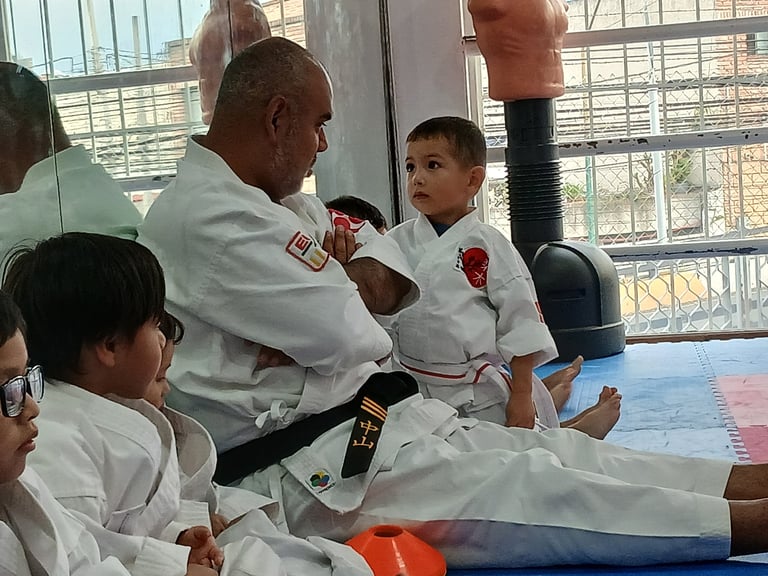 Martial arts instructor teaching young children in white gis during a judo or karate class in a bright gymnasium