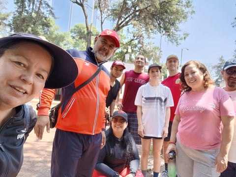 Group of children and adults smiling at camera during outdoor community event in park with trees