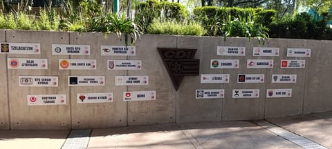 Concrete wall decorated with multiple sponsor and business logos and plaques in various sizes
