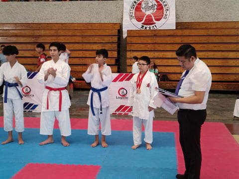 Young karate students in white gis receiving medals at a dojo competition event
