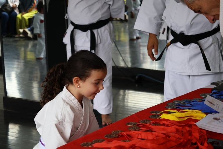 Young martial artist in white gi practices punch on red pad while instructors in white uniforms watch during training class