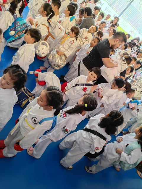 Group of children in martial arts uniforms practicing on blue mats during a karate or judo class training session